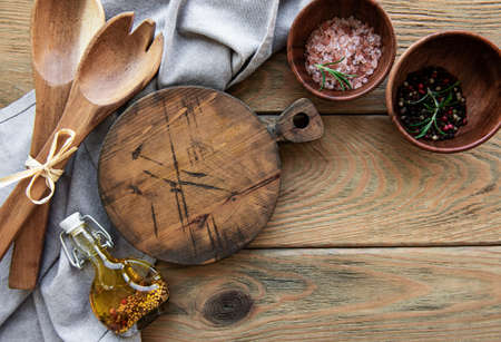 Old vintage kitchen utensils. Wooden spoons, cutting board, napkin and spices over old wooden table....