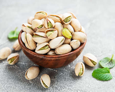 Bowl with pistachios on a gray concrete background