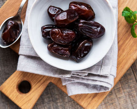 Dried dates fruits in bowl on wooden table.