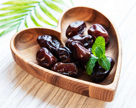 Dried dates fruits in bowl on wooden table.