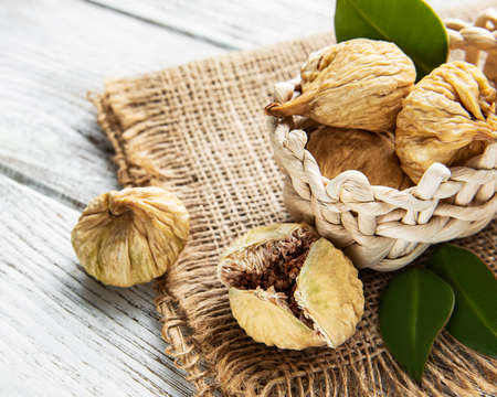 Tasty dried figs in a basket on a white wooden tableの写真素材