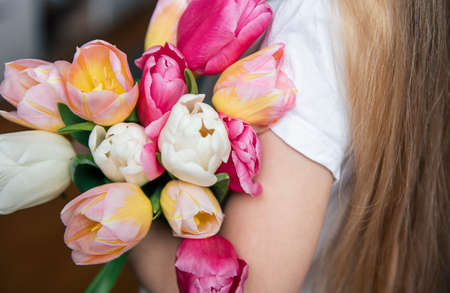 Spring tulips in the hands of a little girl. Mother's day gift.