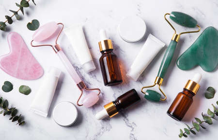 Cosmetic products, essential oils, cream tubes and face roller on a marble backgroundの写真素材