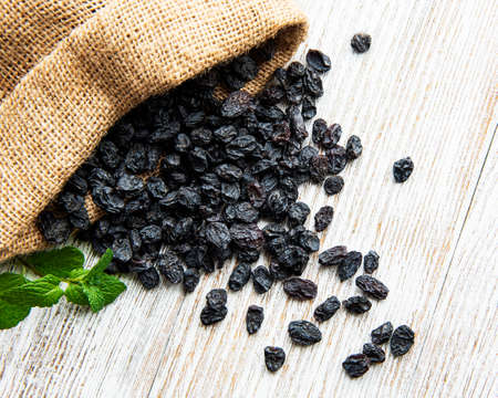 Black dried raisins on a white woodenの写真素材