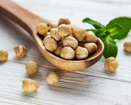 Peeled hazelnuts in a spoon on white wooden backgroundの写真素材
