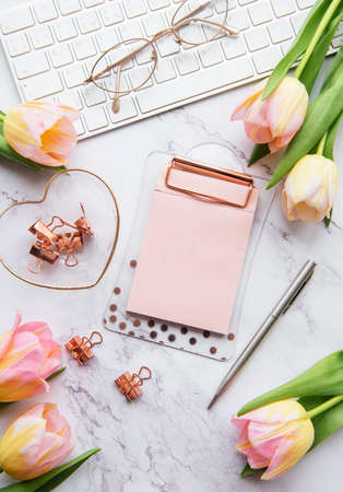 Freelancer or blogger workplace with keyboard, notepad and tulipsの写真素材