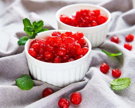 White bowls full of sweet dried cherries on gray textile backgroundの写真素材