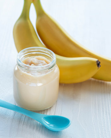Jar of banana puree and bananas on wooden tableの写真素材