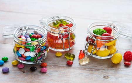 Colorful candies, jelly and marmalade in jars on the tableの写真素材