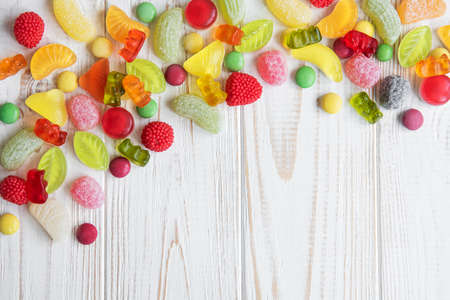 Colorful candies, jelly and marmalade on white wooden background with copy space