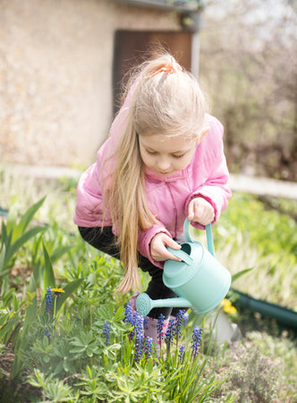 Little girl in a garden with green watering potの写真素材