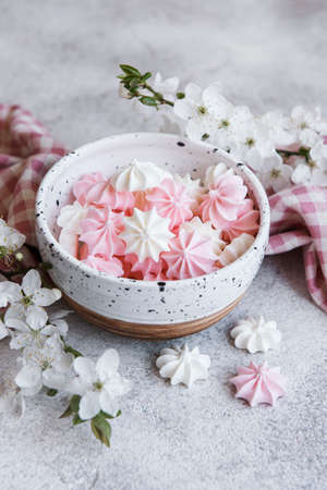 Small white and pink meringues in the ceramic bowl on concrete backgroundの写真素材