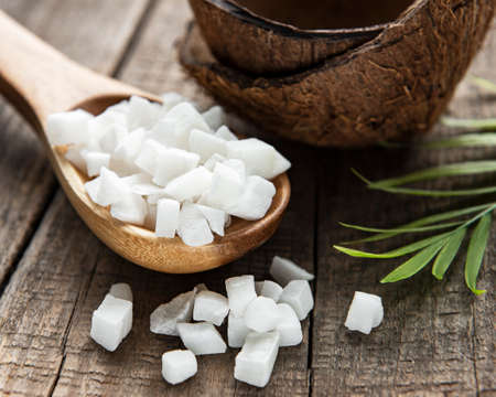 Dried sweet coconut cubes in spoon on wooden table background.の写真素材