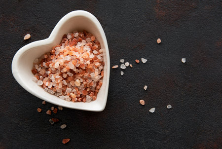 Himalayan pink salt on black background in a heart shape saucerの写真素材