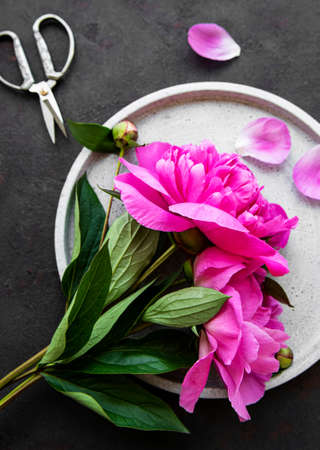 Fresh pink peony flowers on a concrete plate with copy space on black background, flat lay.の写真素材