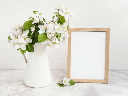 Spring apple blossom in a vase with an empty photo frame on the table