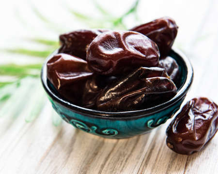 Dried dates fruits in bowl on wooden table.の写真素材