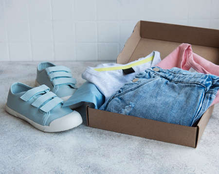 Clothes for kids in an open cardboard box. Online shopping concept. Delivery of clothes.の写真素材