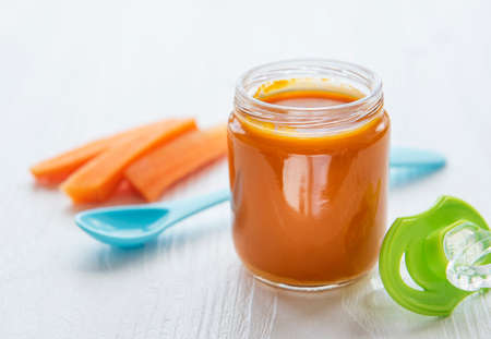 Baby carrot mashed with spoon in glass jar, baby foodの写真素材