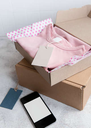 Clothes for kids in an open cardboard box. Online shopping concept. Delivery of clothes.の写真素材