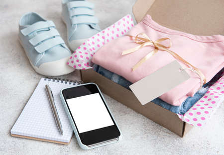 Clothes for kids in an open cardboard box. Online shopping concept. Delivery of clothes.の写真素材