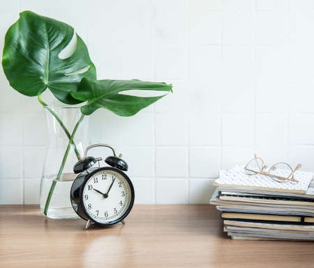 Office desk with stack of notepads, alarm clock, office supplies and house plants