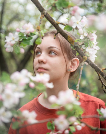 A young girl in a blooming garden looks at flowering treesの写真素材