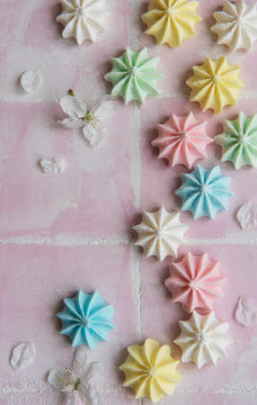 Small colorful meringues on pink tile background