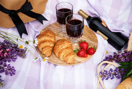Romantic picnic scene on summer day. Outdoor picnic with wine and a fruit in the open air on the background of green grass.の写真素材