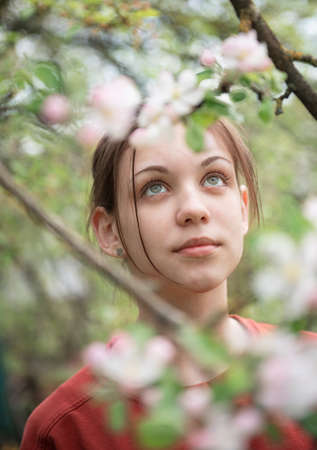 A young girl in a blooming garden looks at flowering treesの写真素材