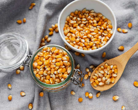 Dry Corn seeds in jar and bowl on gray textile background