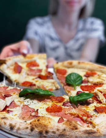 Pizza with pizza sauce, mozzarella cheese and pepperoni. Pizza on the table in a restaurantの写真素材