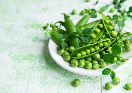 Fresh green peas pods and green peas with sprouts on green wooden background. Concept of healthy eating, fresh vegetables.の写真素材