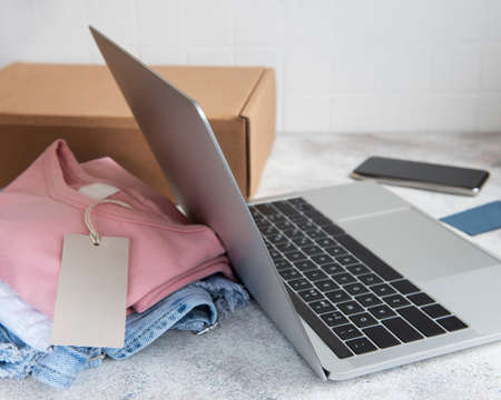 Online shopping concept. A laptop and a set of women's clothing in a cardboard box. Delivery of clothes.の写真素材