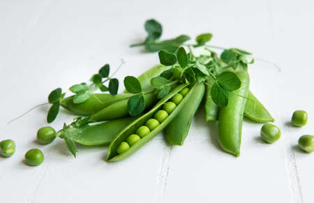 Fresh green peas pods and green peas with sprouts on white tile background. Concept of healthy eating, fresh vegetables.の写真素材