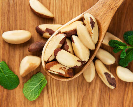 Spoon with Brazil nuts on wooden tableの写真素材
