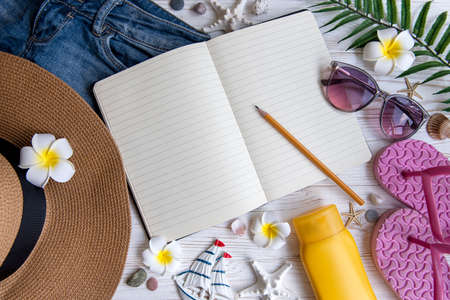 Summer vacation concept. Straw hat, open notebook and beach accessories with seashells and starfish...