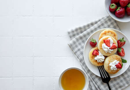 Cottage cheese pancakes, ricotta fritters on ceramic plate with fresh strawberry. Healthy and...