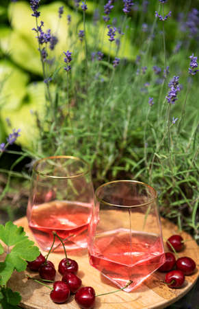 Picnic outdoors in lavender fields. Rose wine in a glass, cherries on a wooden boardの写真素材