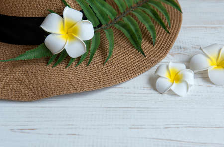 Summer vacation concept. Straw hat and beach accessories with frangipani flowers on white wooden...