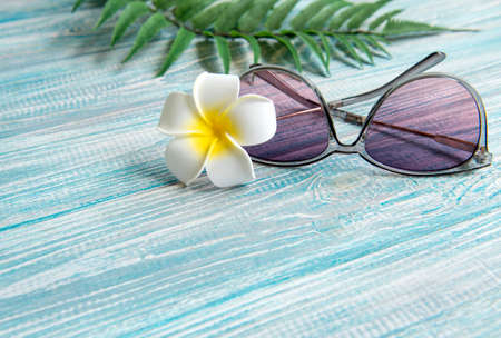 Summer vacation concept. White frangipani flower, sunglasses on a blue wooden backgroundの写真素材