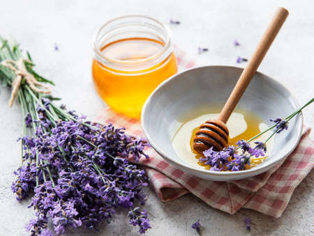 Jar with honey and fresh lavender flowers on a concrete backgroundの写真素材