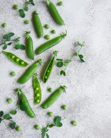 Fresh green peas pods and green peas with sprouts on concrete background. Concept of healthy eating, fresh vegetables.の写真素材