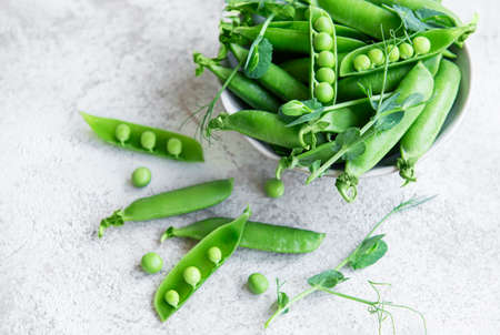 Fresh green peas pods and green peas with sprouts on concrete background. Concept of healthy eating, fresh vegetables.の写真素材