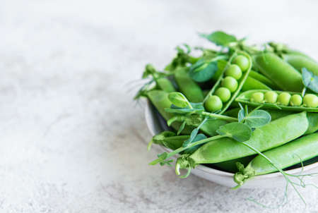 Fresh green peas pods and green peas with sprouts on concrete background. Concept of healthy eating, fresh vegetables.の写真素材