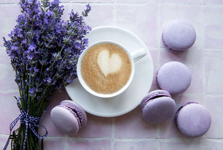 Cup of coffee with lavender-flavored macaroon dessert on pink tiles backgroundの写真素材