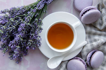Cup of tea with lavender-flavored macaroon dessert on pink tiles backgroundの写真素材
