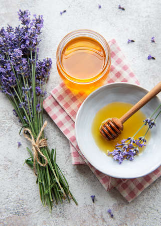 Jar with honey and fresh lavender flowers on a concrete backgroundの写真素材