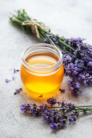 Jar with honey and fresh lavender flowers on a concrete backgroundの写真素材