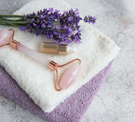 Lavender spa. Essential oils, face roller, towels. Natural herb cosmetic with lavender flowersの写真素材